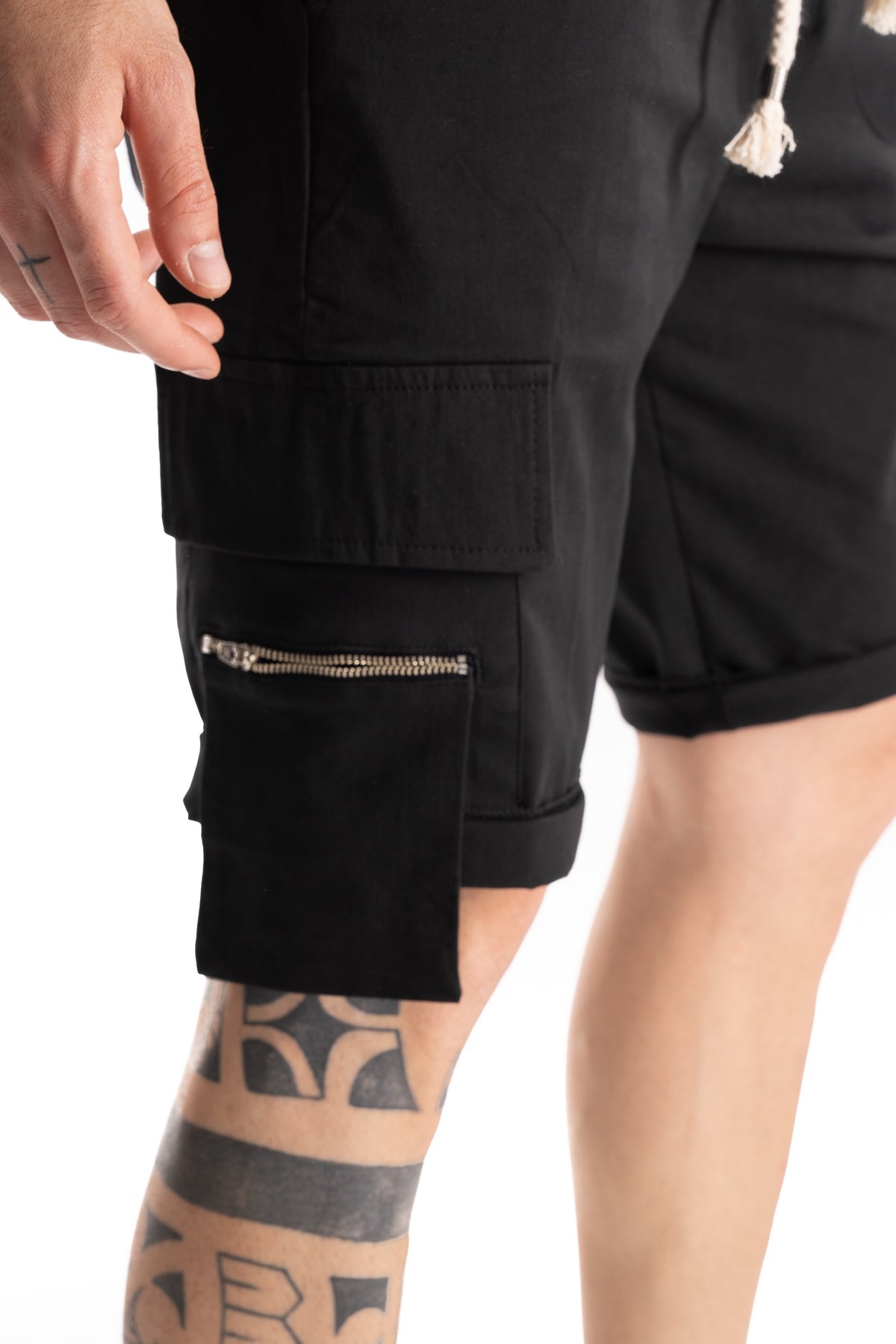 Detail view of a black cargo pocket with silver zipper and stitched flap